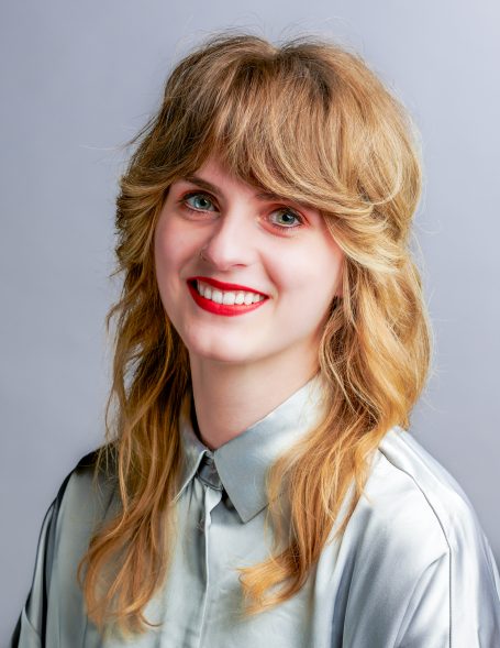 Kleurportret van een glimlachende vrouw tegen een grijze achtergrond